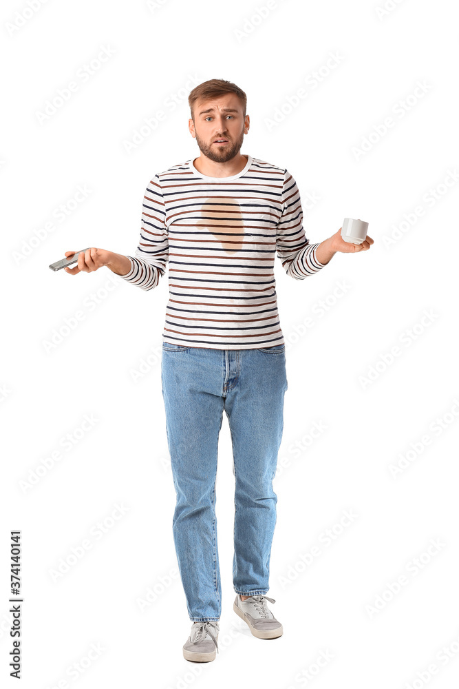 Stressed young man with coffee stains on his t-shirt and mobile phone on white background