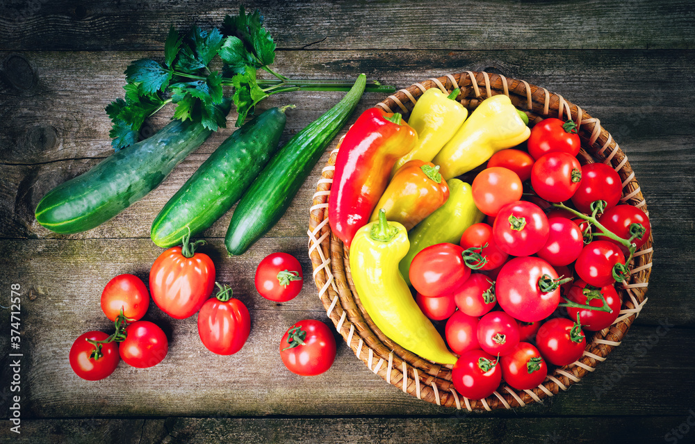 Harvest of fresh ripe vegetables on wooden table and in rod bowl - pepper, tomato, cucumber, celery 