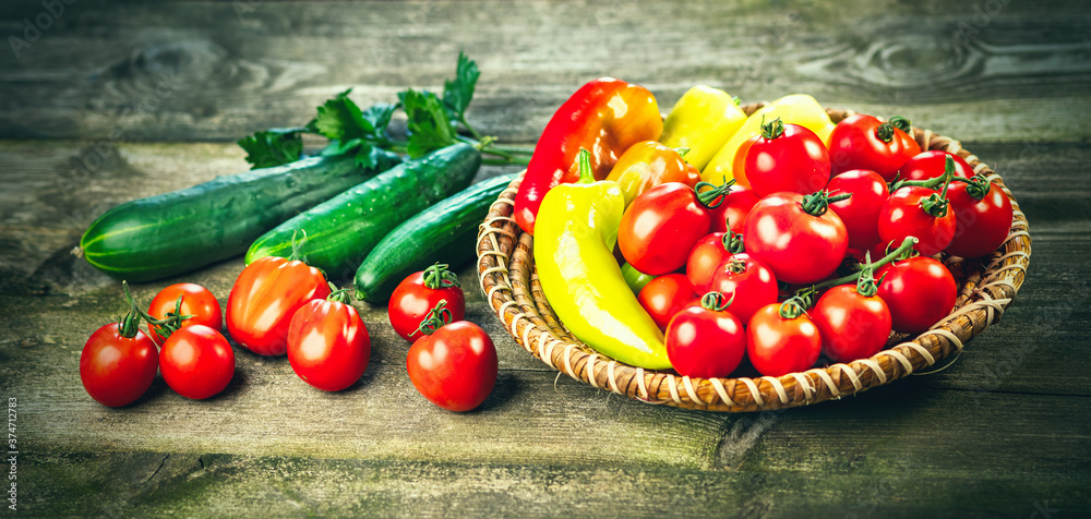 在木桌和杆碗中收获新鲜成熟的蔬菜——胡椒、番茄、黄瓜、芹菜