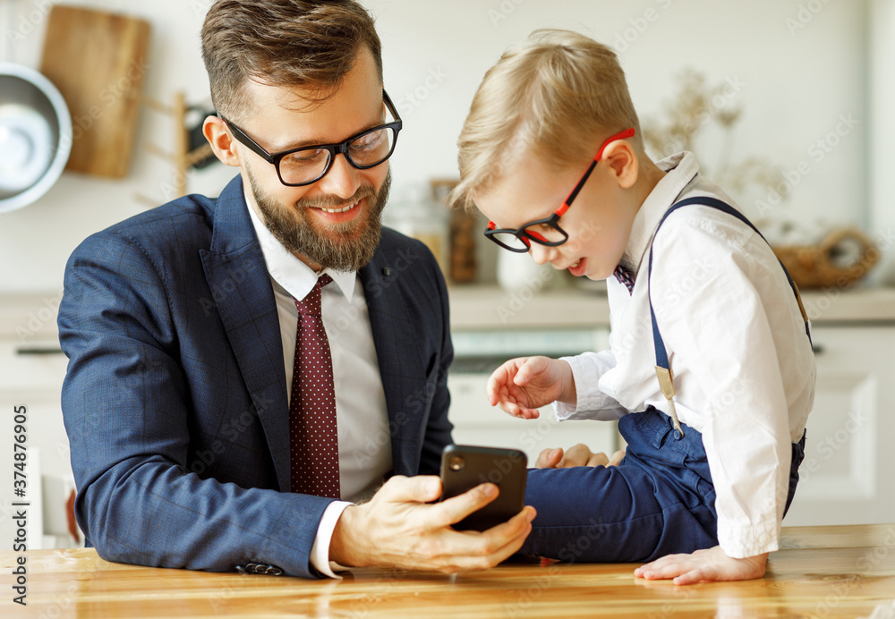 商人父亲和一个年轻的小学生儿子在看智能手机。