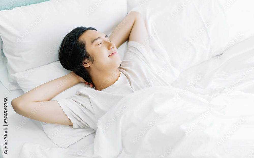 亚洲年轻男子早上睡在床上放松时微笑的俯视图。休息吧