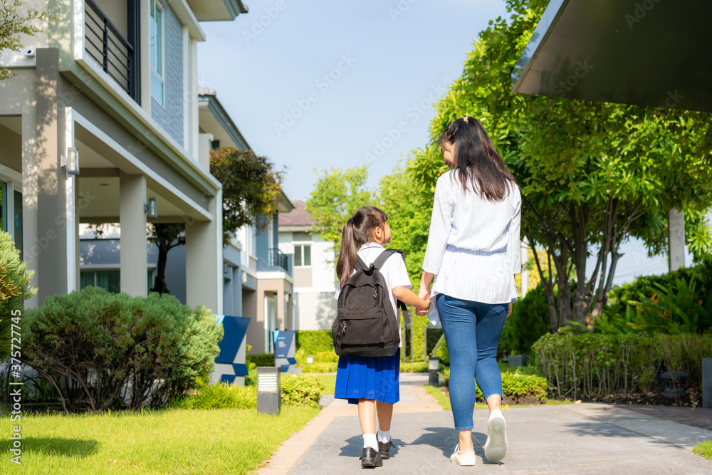 快乐的亚洲母女小学生在早校路蒂步行上学