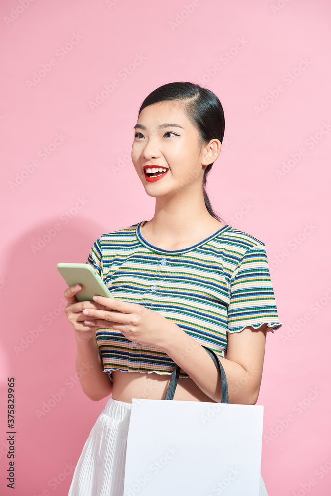 年轻、兴奋、快乐的女人拿着购物袋的照片，用mobi将购物袋隔离在粉色背景下