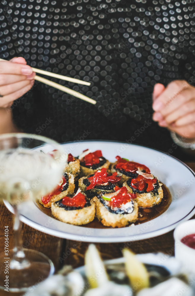 女孩在日本餐厅用筷子吃烤寿司。日本料理、快餐、海鲜