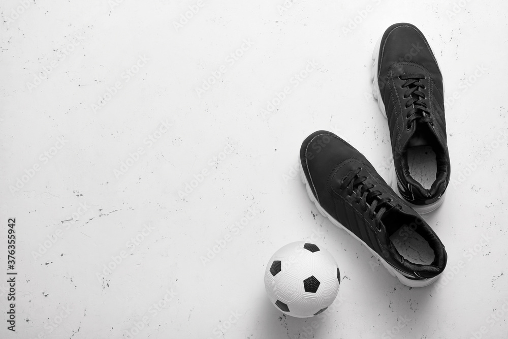 Pair of sportive male shoes and soccer ball on light background