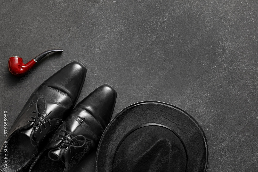 一双灰色背景的皮鞋、帽子和烟筒