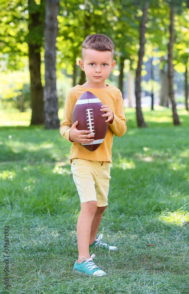 小男孩在户外踢美式足球
