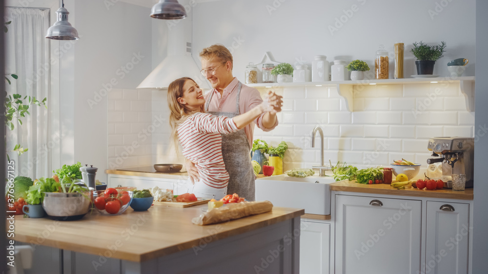 Handsome Young Man in Pink Shirt and Apron and Beautiful Girl in Striped Jumper are Creatively Danci
