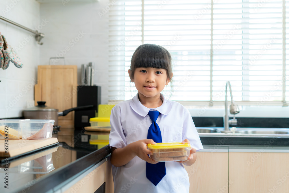 穿着制服的亚洲小学生女孩在早校做午餐盒三明治