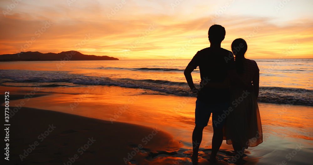 情侣站在日落海滩上