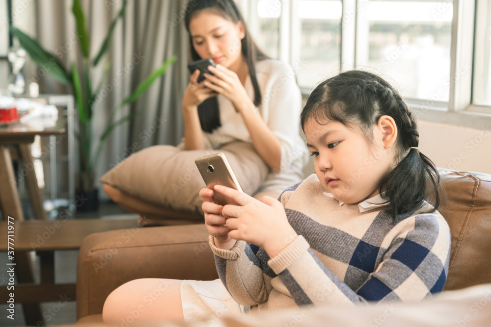 亚洲家庭母女在客厅用智能手机共度周末