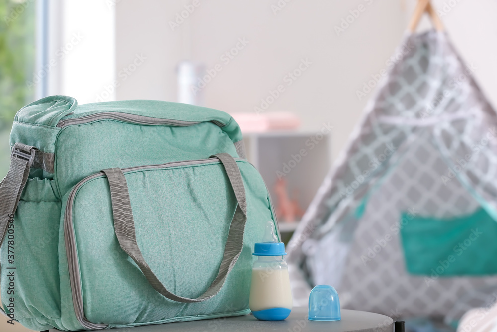 Bottle of milk for baby with bag on table in room