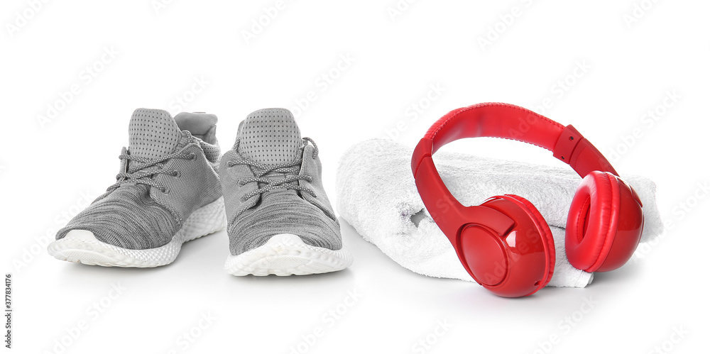 Sportive shoes, towel and headphones on white background