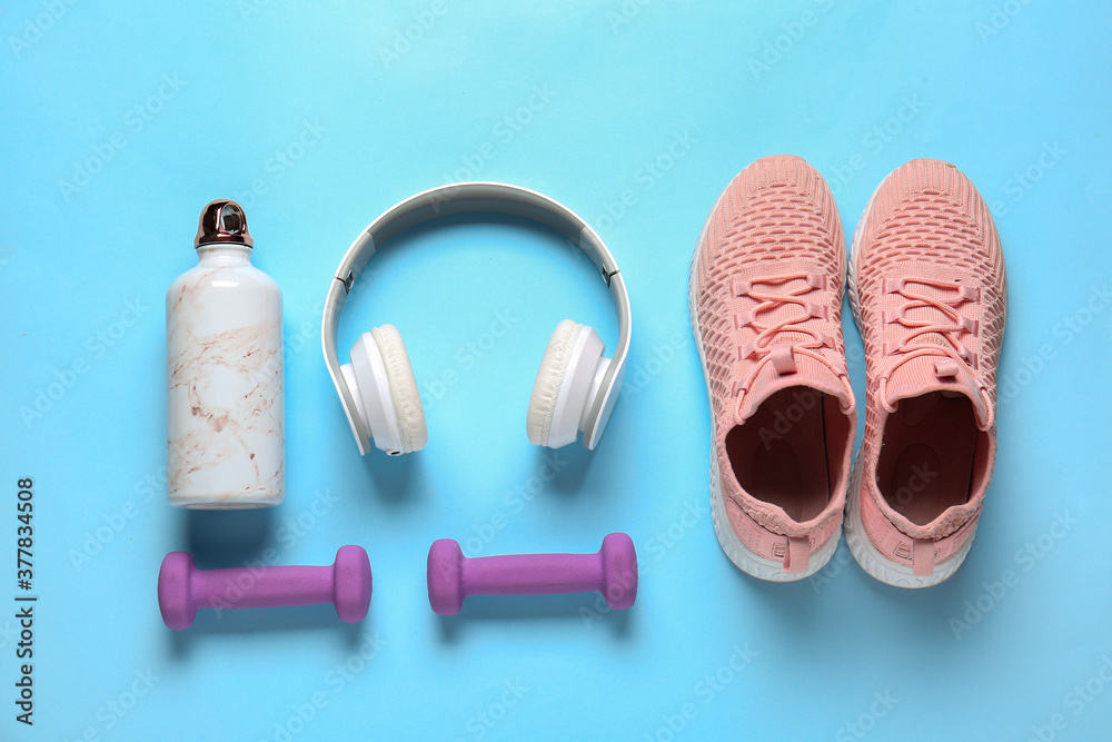 彩色背景的运动鞋、水瓶、哑铃和耳机