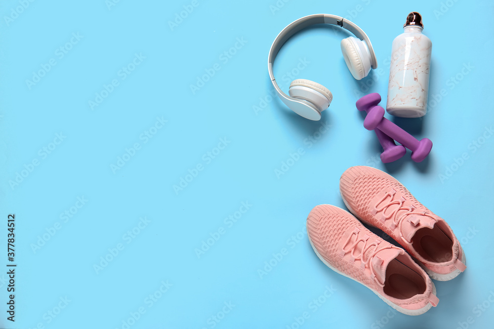 彩色背景的运动鞋、水瓶、哑铃和耳机