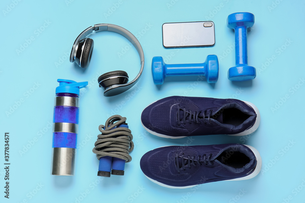 彩色背景的运动鞋、哑铃、跳绳、水瓶和耳机