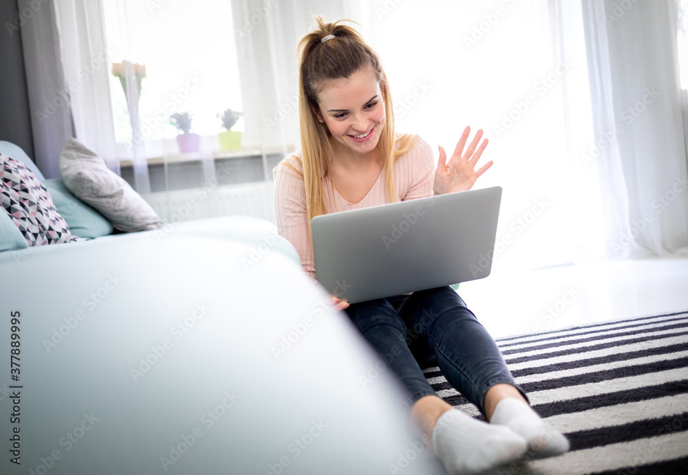 快乐的年轻女人坐在家里用笔记本电脑视频聊天