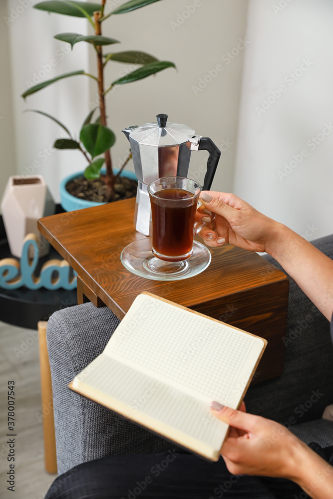 在家沙发上喝咖啡看书的女人