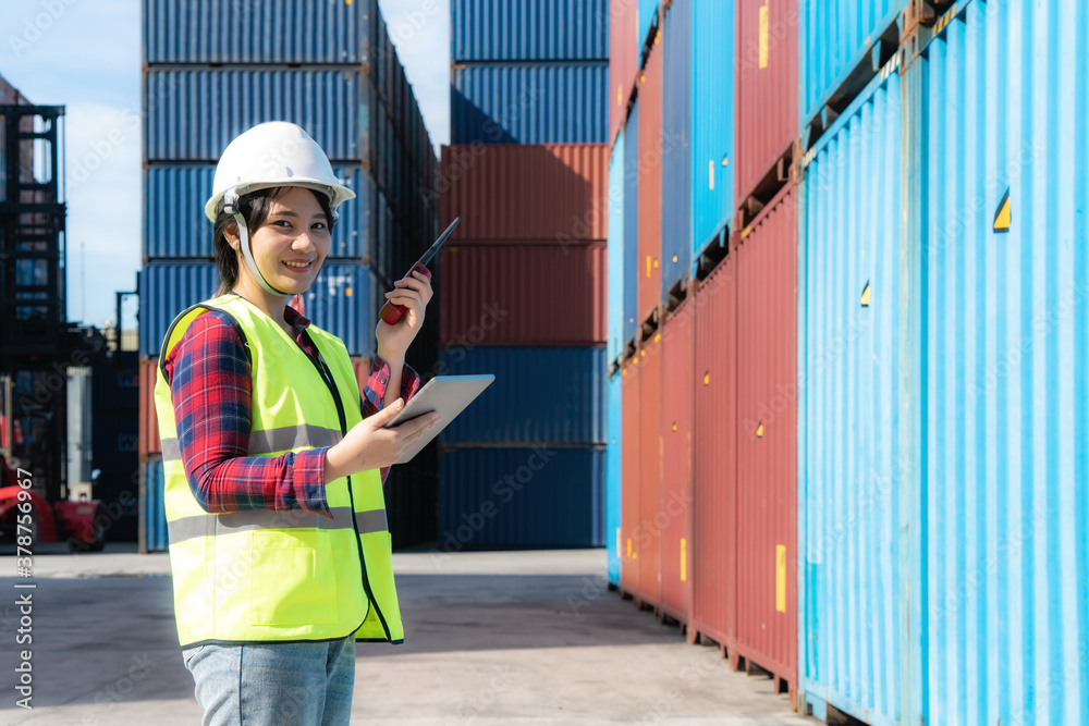 Engineer woman or Foreman manager in container depot working with digital tablet and walkie talkie f