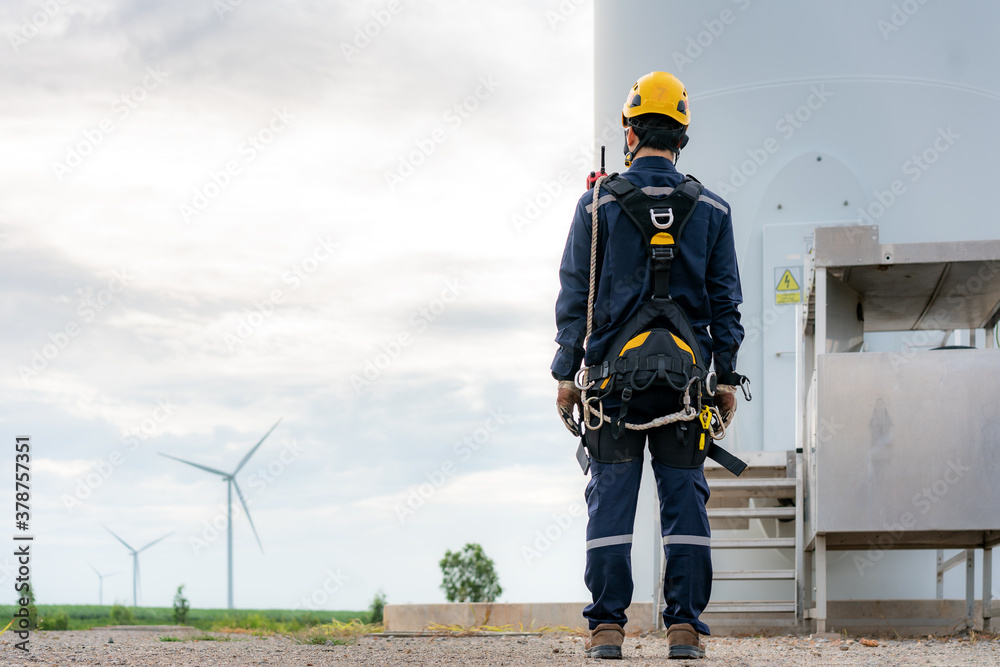 Asian man Inspection engineer preparing and progress check of a wind turbine with safety in wind far