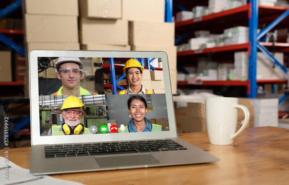 Warehouse staff talking on video call at computer screen in storage warehouse . Online software tech