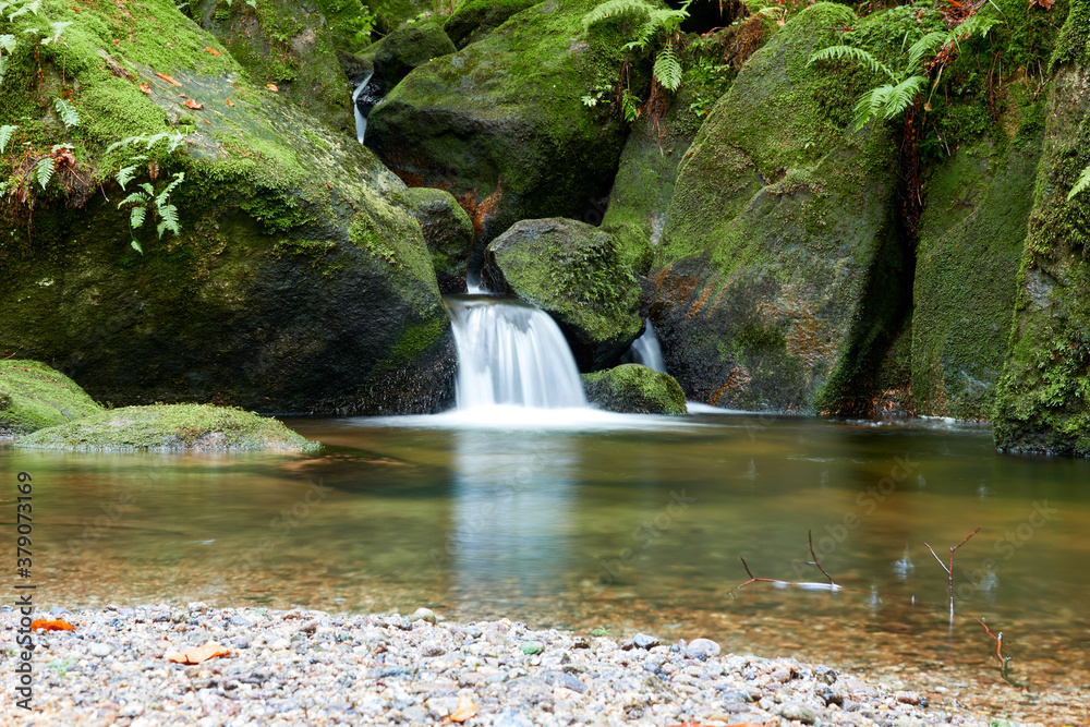 Small cascade of the Gertelbach waterfall, pebbles in the shade of blue form the foreground.Buehlert