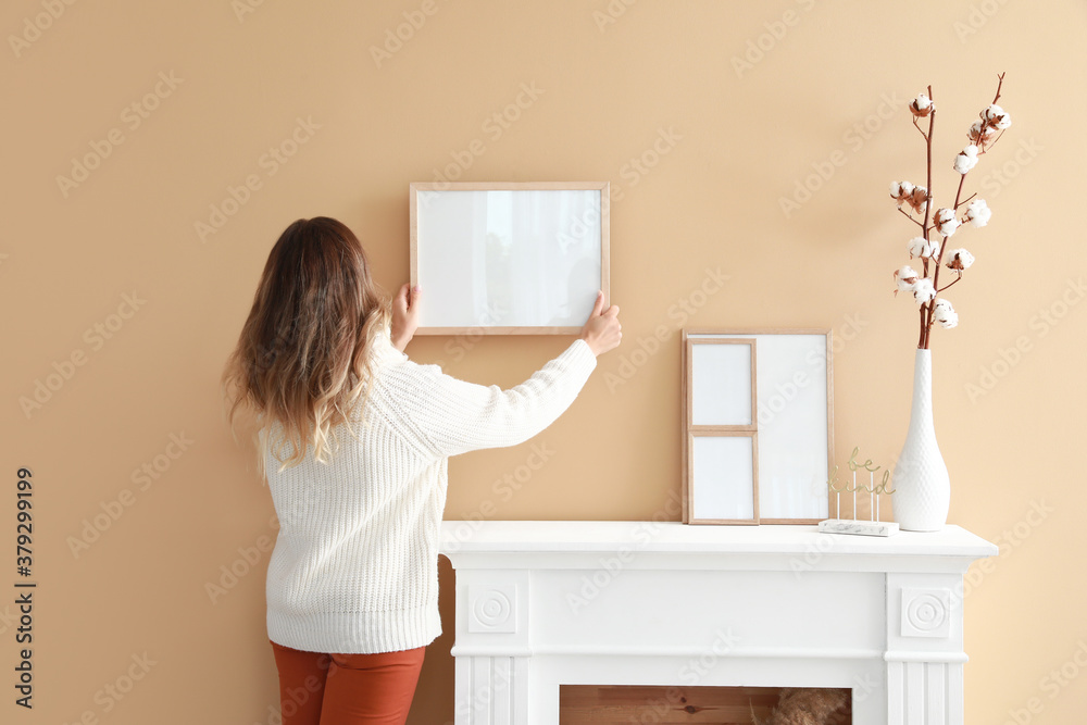 Woman hanging blank photo frame on wall