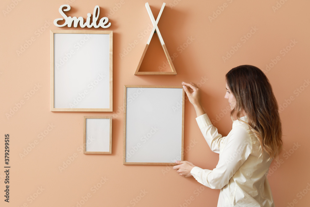 Woman hanging blank photo frames on wall