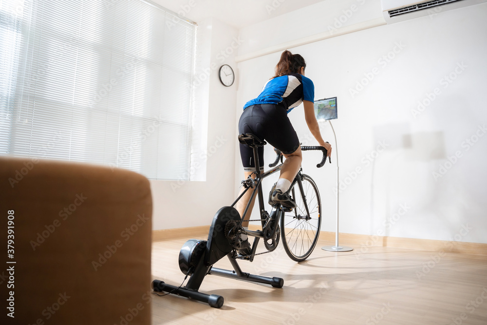 Asian woman cyclist. She is exercising in the home.By cycling on the trainer and play online bike ga