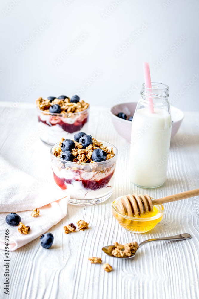 Cooking breakfast with granola and berries on white kitchen background