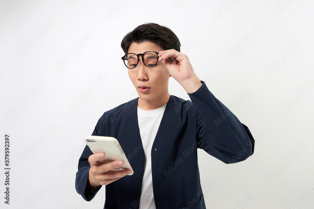 Surprised happy Asian man holding phone looking at cellphone read good news over white background.