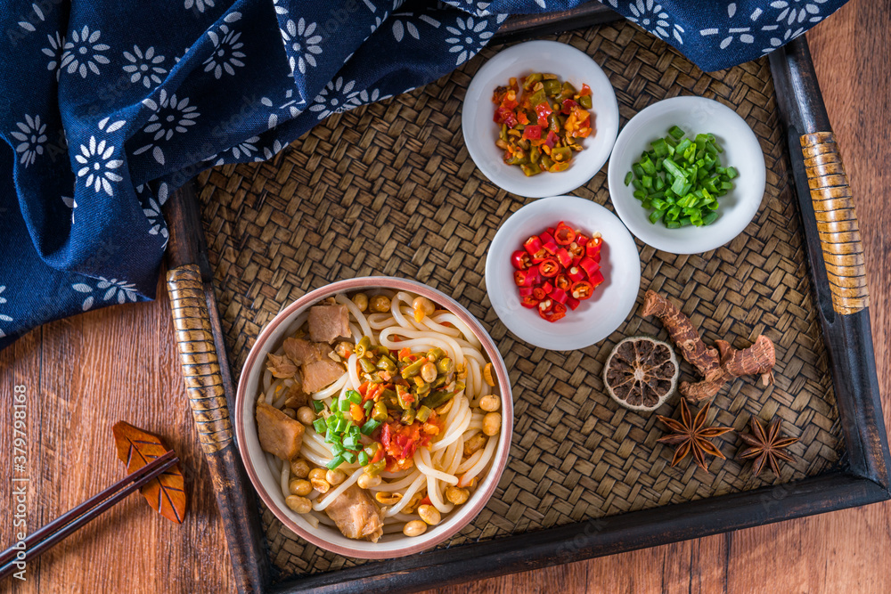 A bowl of Guilin rice noodles placed in a rattan tray