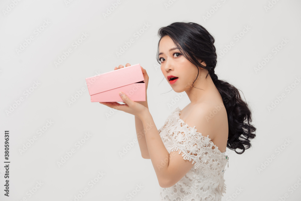 Amazed young Asian woman opening the pink gift box over white background.