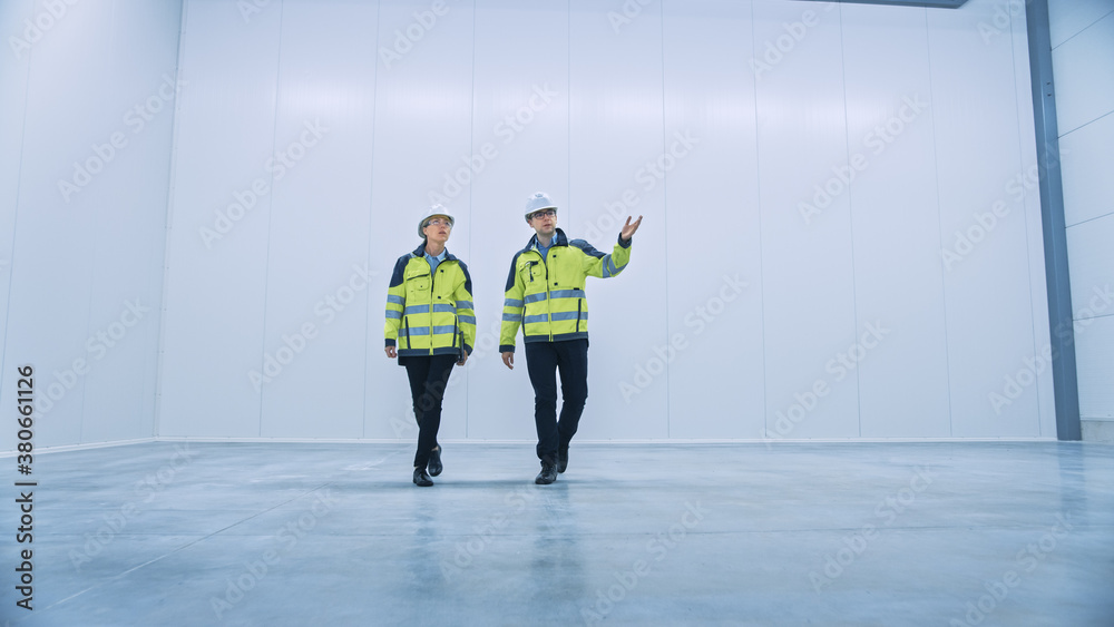 Two Engineers Talking, Walking Across Empty Factory Floor, Inspecting, Planning Where All the Machin