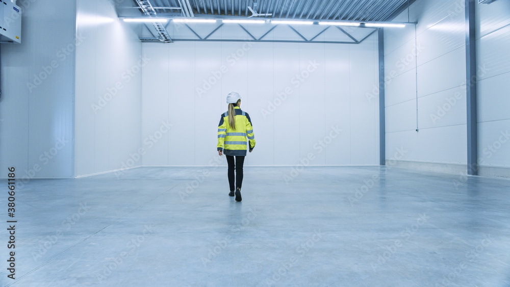 Female Engineer Wearing Safety Hat Walks Across Empty Factory Floor, Inspecting, Planning Future Fac