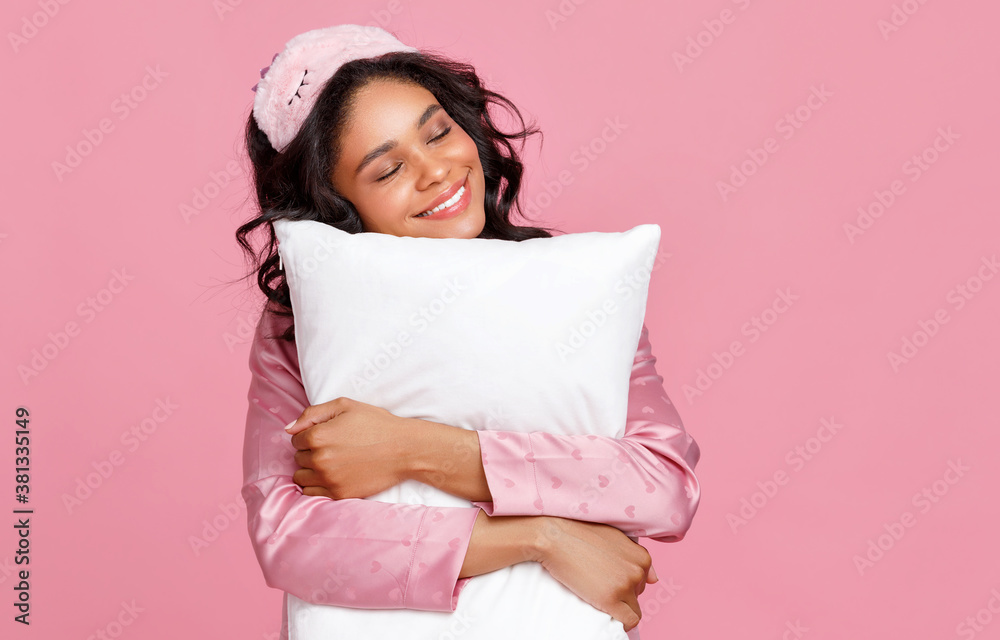 Optimistic young woman hugging pillow.
