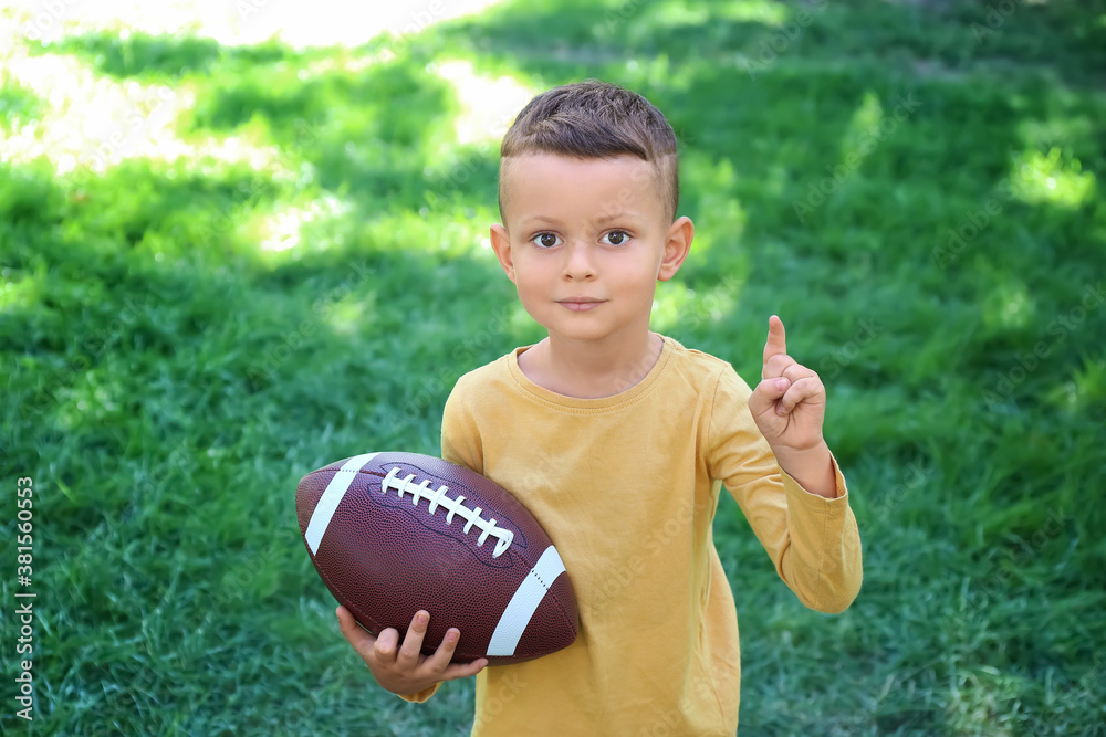 Little boy playing American football outdoors