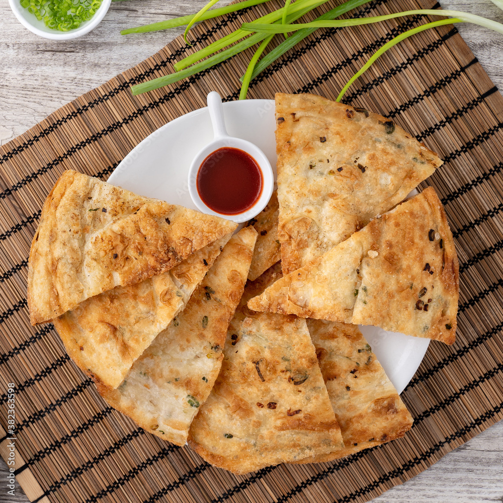 Taiwanese food - delicious flaky scallion pie pancakes on bright wooden table background, traditiona