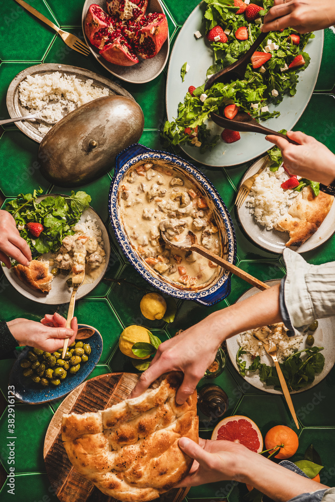 Family having Turkish style dinner. Flat-lay of people hands over table with lamb in yogurt sauce, a