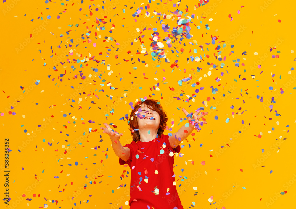happy birthday! ginger child boy with confetti on yellow background