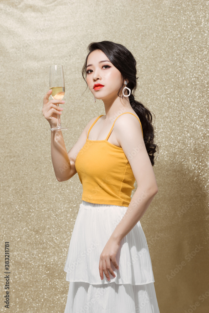 Indoor shot of positive attractive young female in evening dress with glass of champagne,