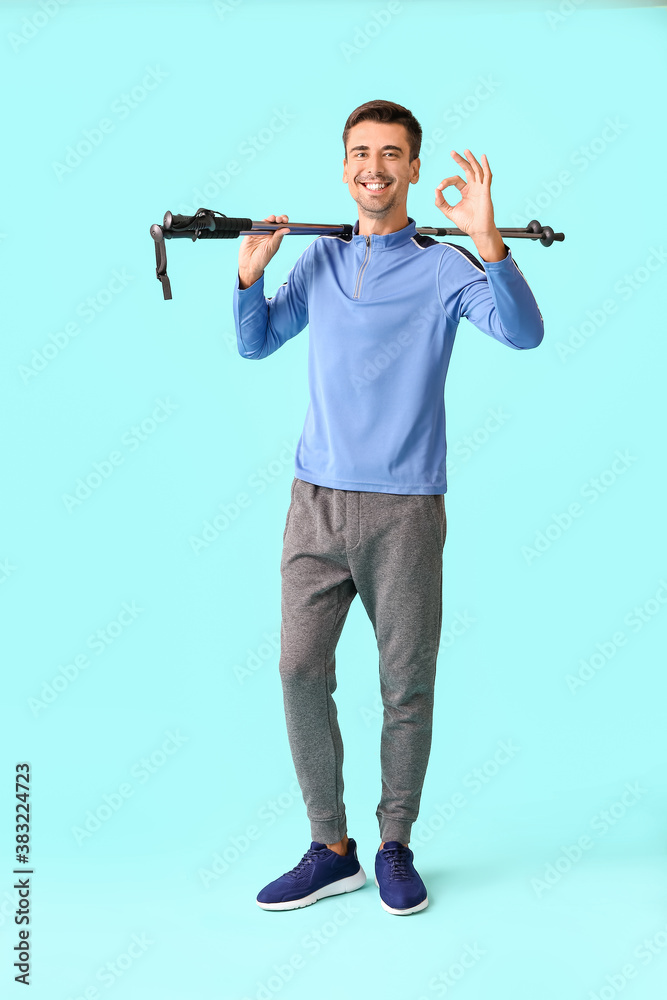 Young man with walking poles showing OK on color background
