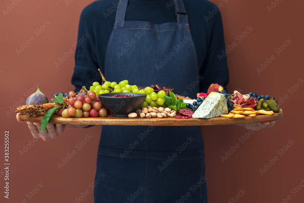 Man in apron holding charcuterie board, front view