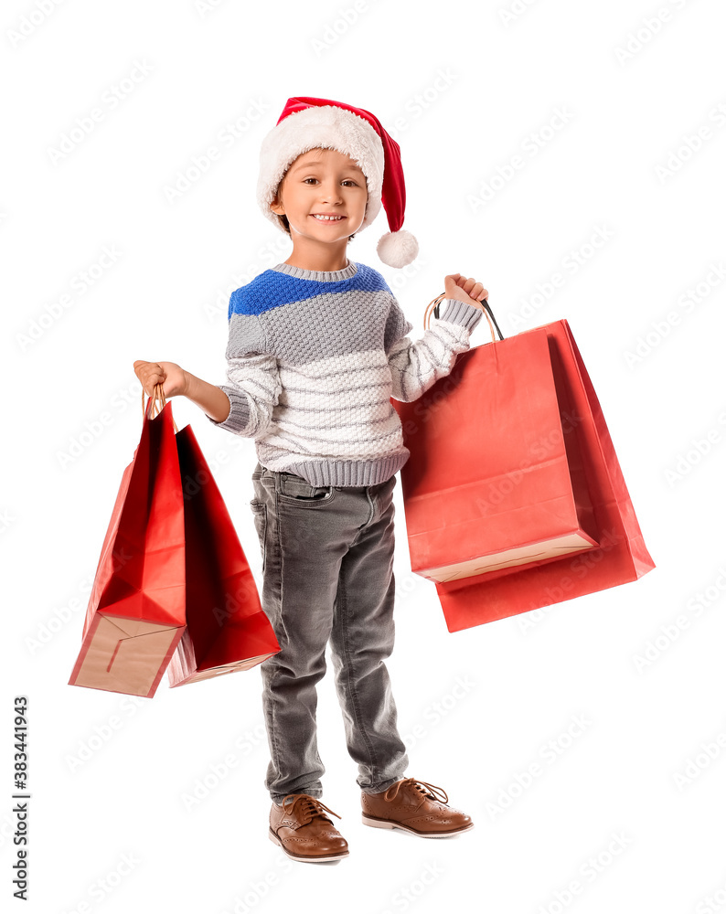 Cute little boy in Santa hat and with shopping bags on white background