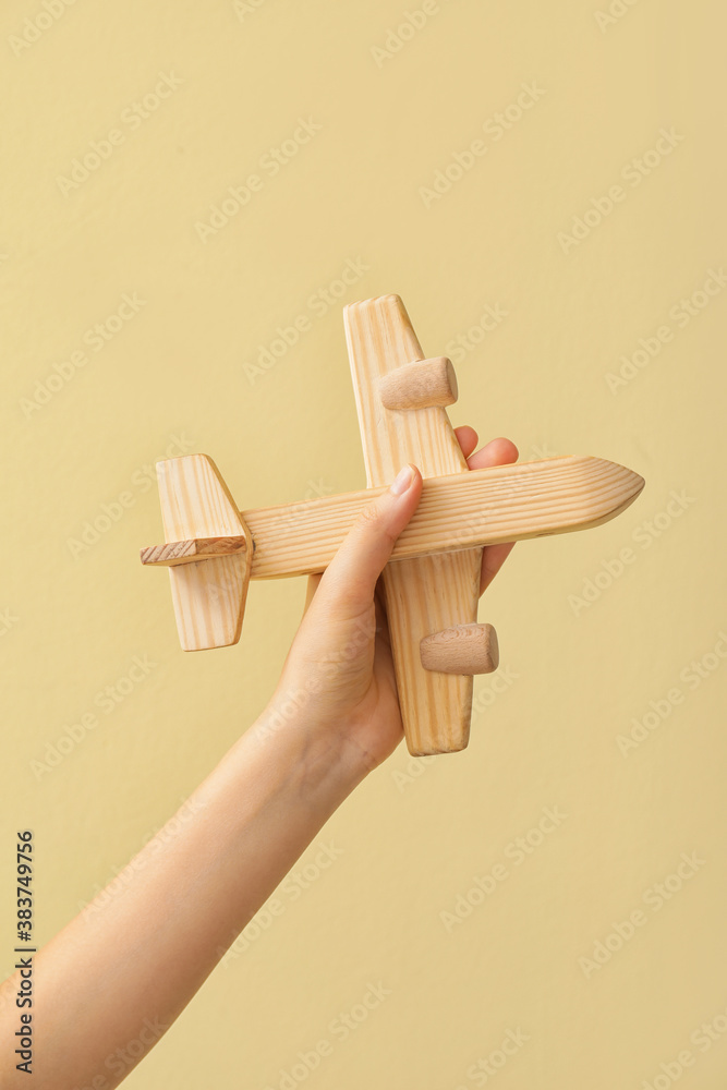 Female hand with wooden airplane on color background