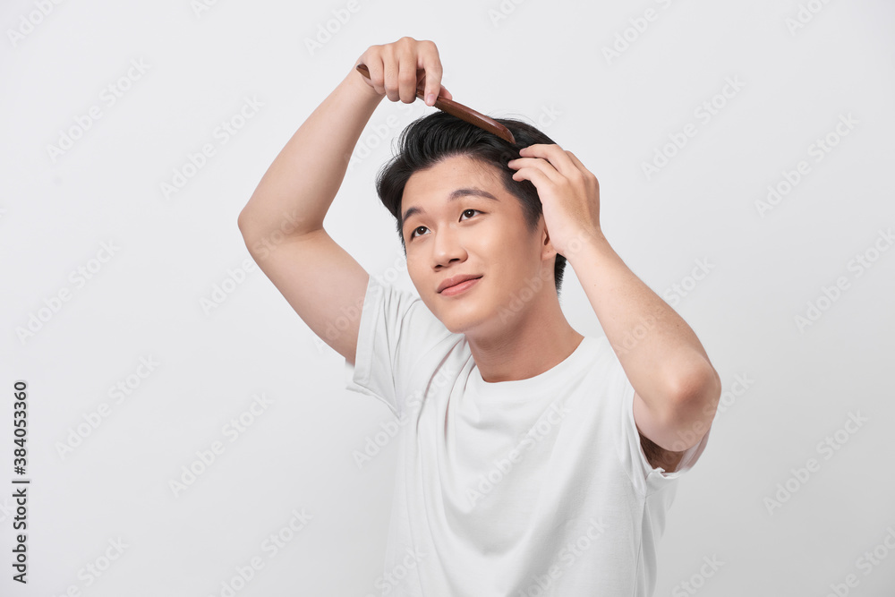 beauty, grooming and people concept - smiling young man brushing hair with comb over white backgroun