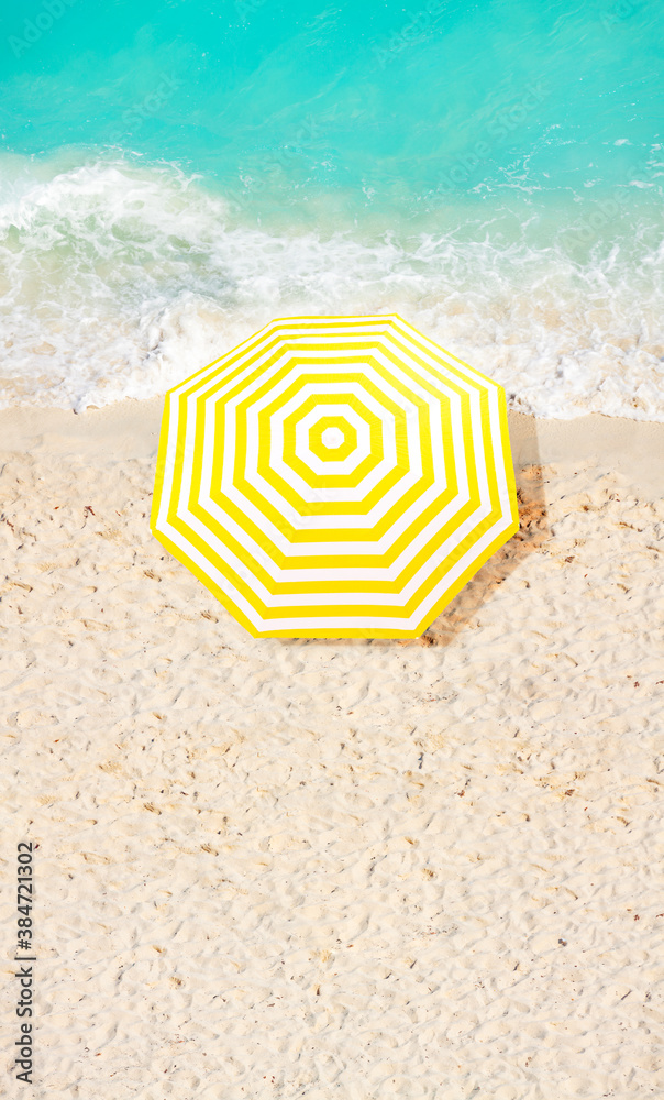 View from above of beach umbrella on the sand near ocean surf waves