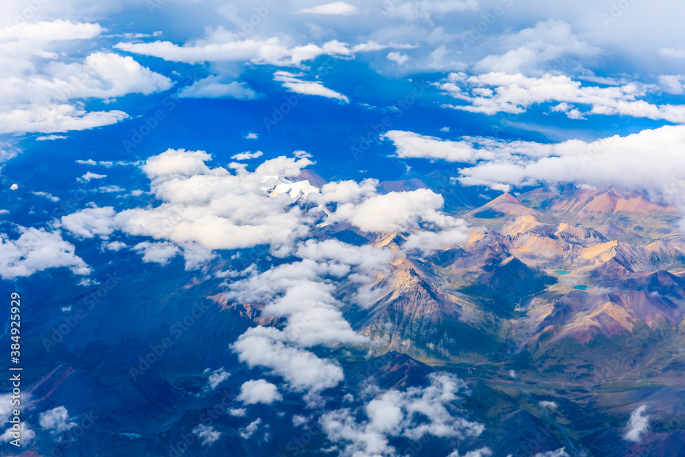 在阳光明媚的日子里俯瞰云朵和五颜六色的山脉。从飞机上俯瞰山脉。