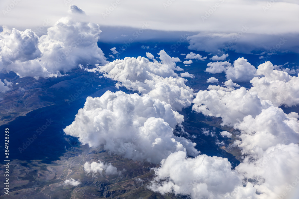 阳光明媚的日子里，云层和山峰上方的鸟瞰图。飞机上的山景。