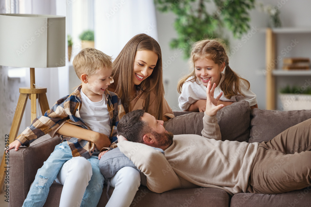 幸福的家庭，母亲，父亲和孩子在家的沙发上。